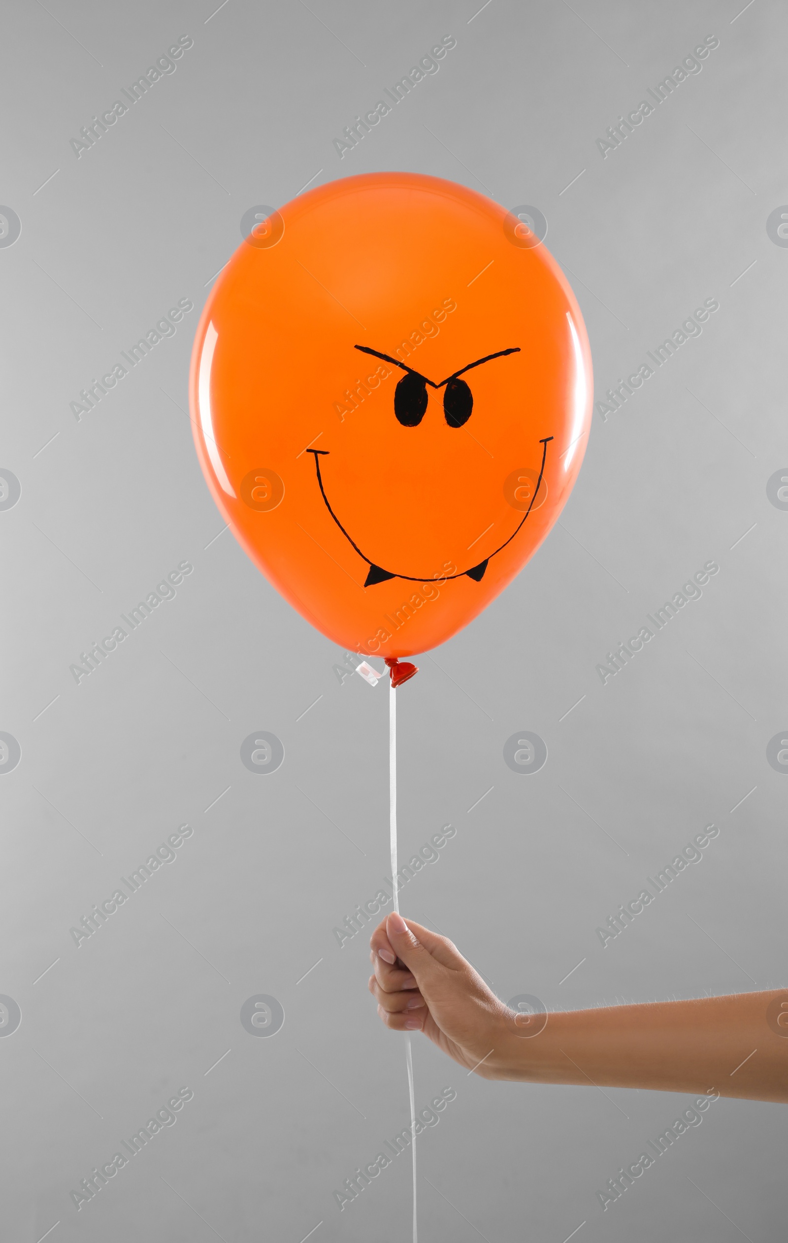 Photo of Woman holding spooky balloon for Halloween party on light grey background, closeup