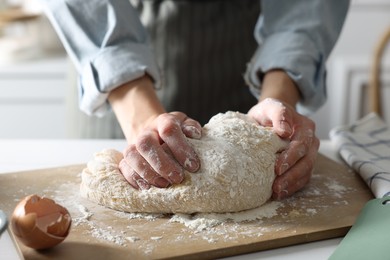 Photo of Woman kneading dough at white wooden table in kitchen, closeup