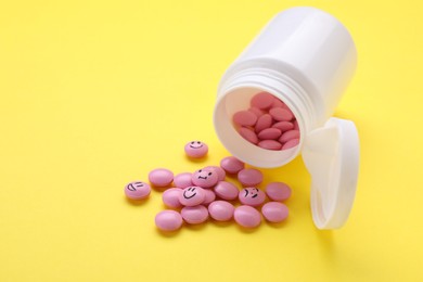 Photo of Pink antidepressants with different emoticons on yellow background
