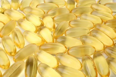 Photo of Many yellow vitamin capsules on white background, closeup