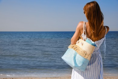 Photo of Woman with beach bag near sea, back view. Space for text