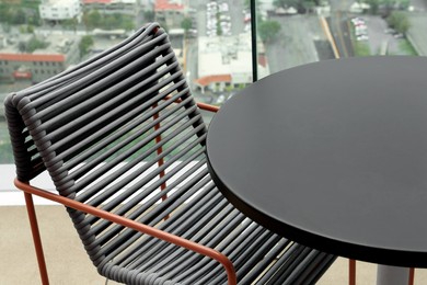 Photo of Coffee table and chair against picturesque landscape of city in cafe, closeup