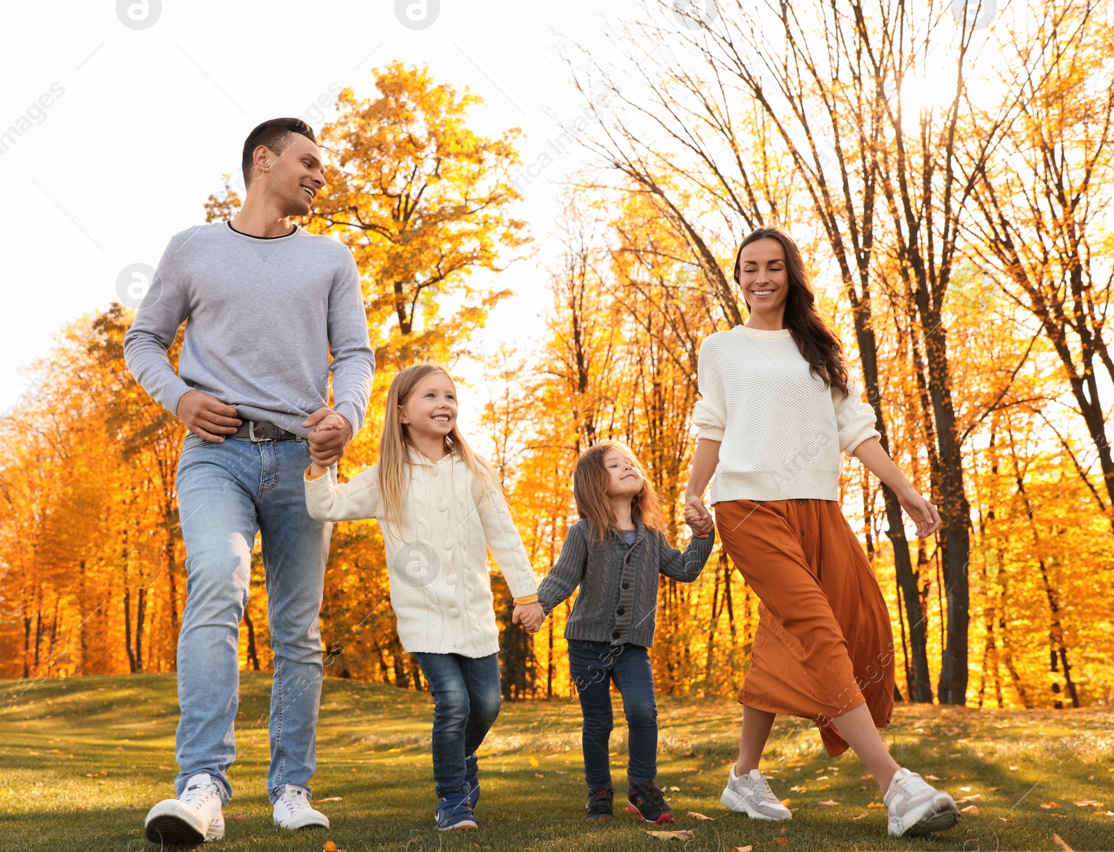 Photo of Happy family with little daughters walking in autumn park