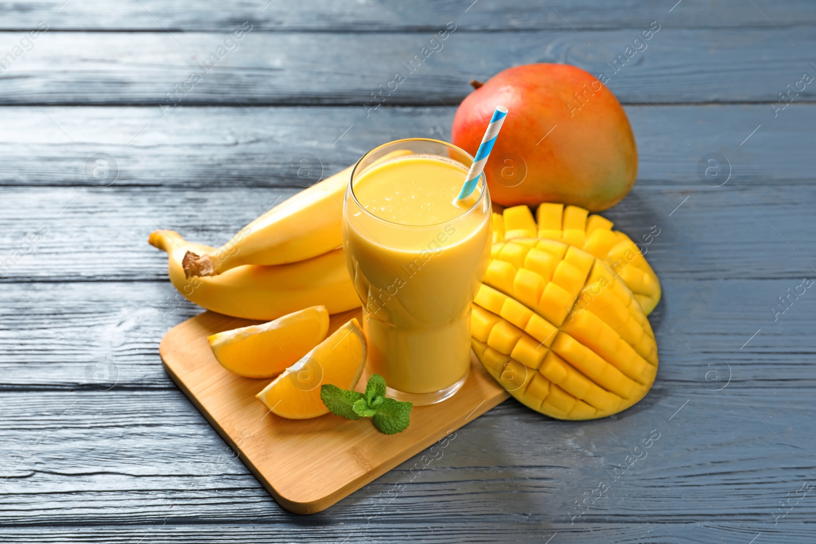 Photo of Tasty tropical drink with mango and fresh fruits on wooden table