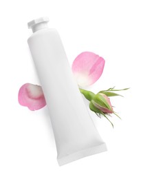 Tube of hand cream and roses on white background, top view