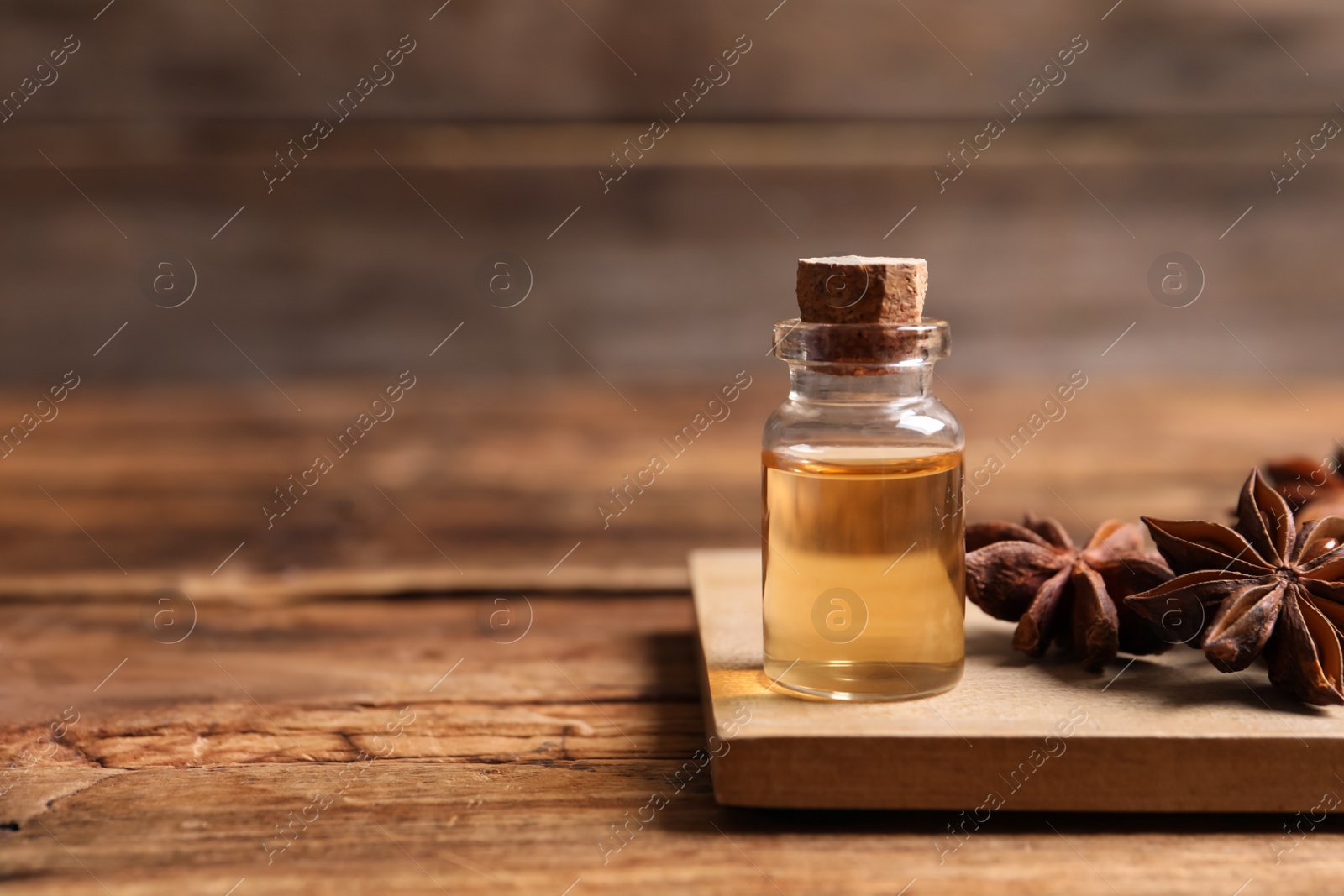 Photo of Bottle of essential oil and anise on wooden table. Space for text