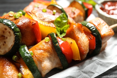 Photo of Delicious chicken shish kebabs with vegetables and basil on black table, closeup