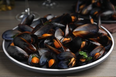 Photo of Plate of cooked mussels with parsley on table, closeup