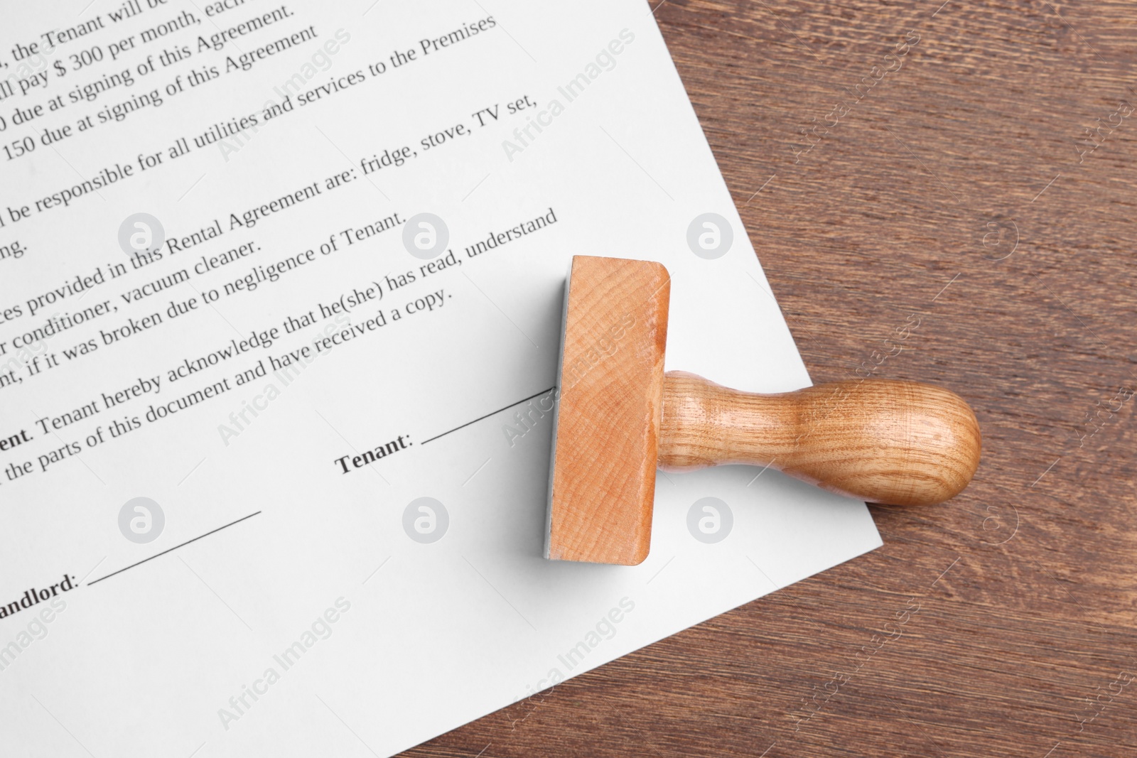 Photo of One stamp tool and document on wooden table, top view