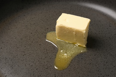 Photo of Frying pan with piece of melting butter, closeup