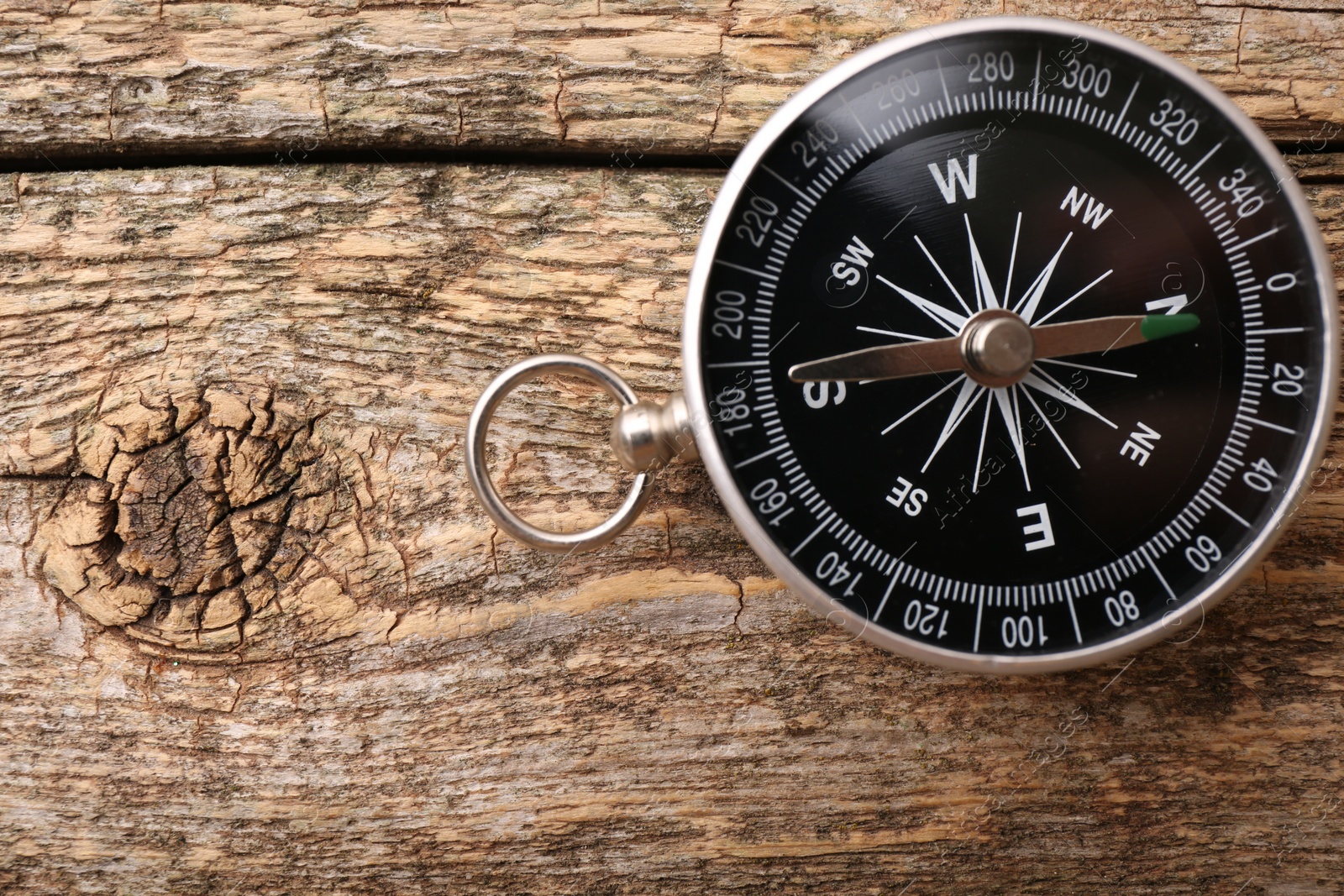 Photo of One compass on wooden table, top view. Space for text