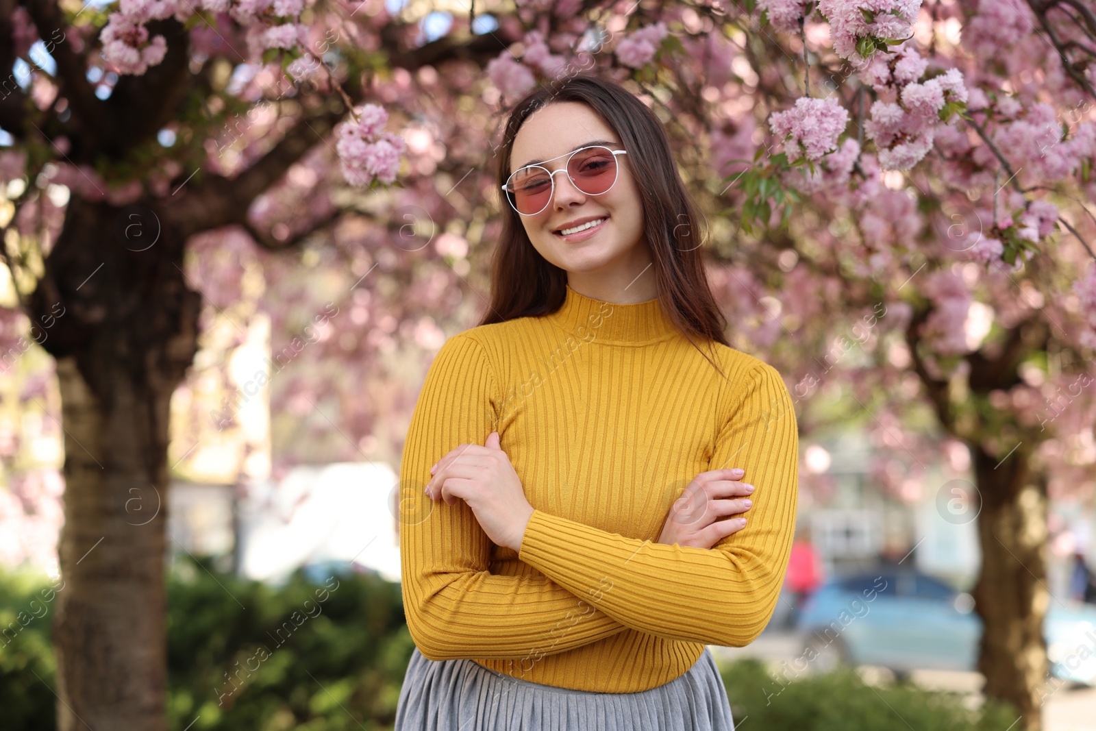 Photo of Beautiful woman in sunglasses near blossoming tree on spring day