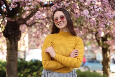 Beautiful woman in sunglasses near blossoming tree on spring day