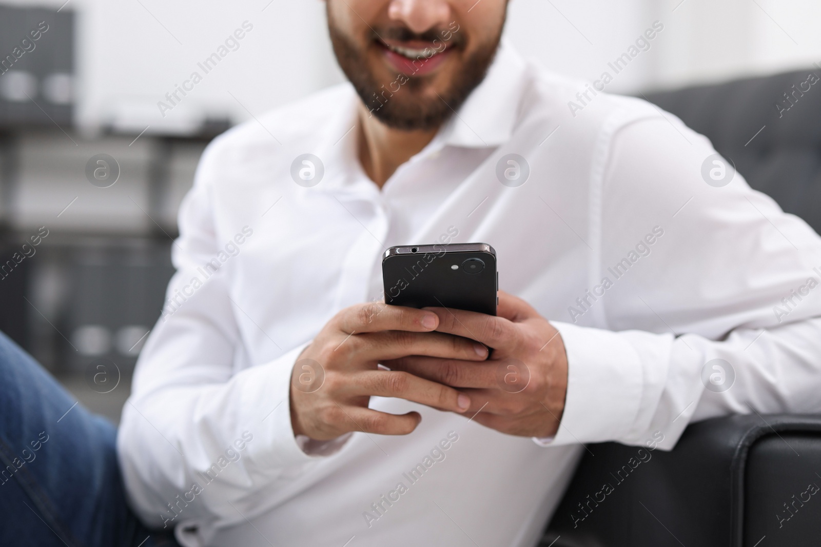 Photo of Young man using smartphone indoors, selective focus