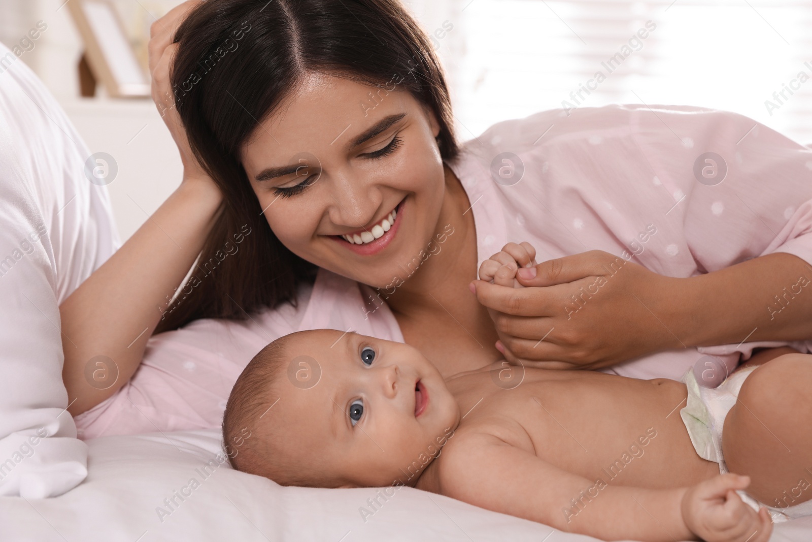 Photo of Happy young mother with her cute baby on bed at home