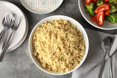 Flat lay composition with cooked quinoa in plate on table