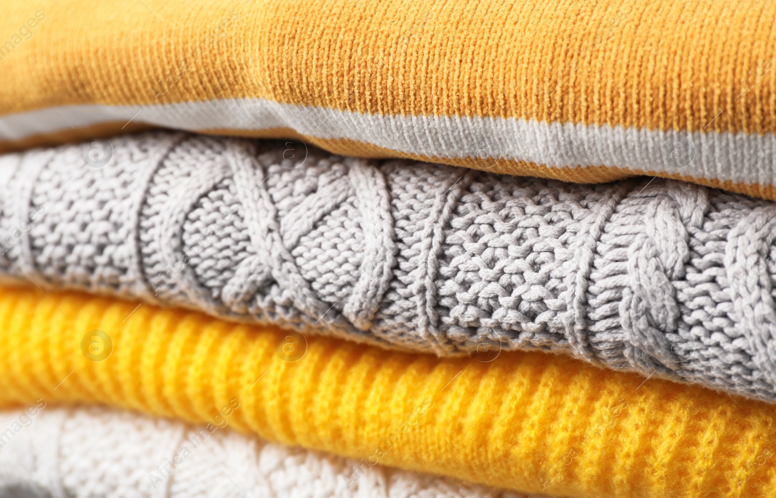 Photo of Stack of folded warm knitted sweaters, closeup