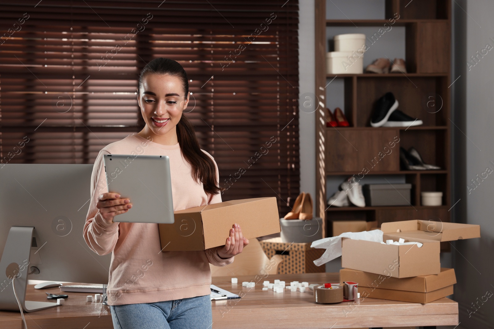 Photo of Seller with tablet and parcel in office. Online store