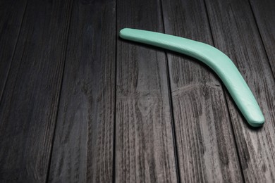 Boomerang on black wooden background. Space for text