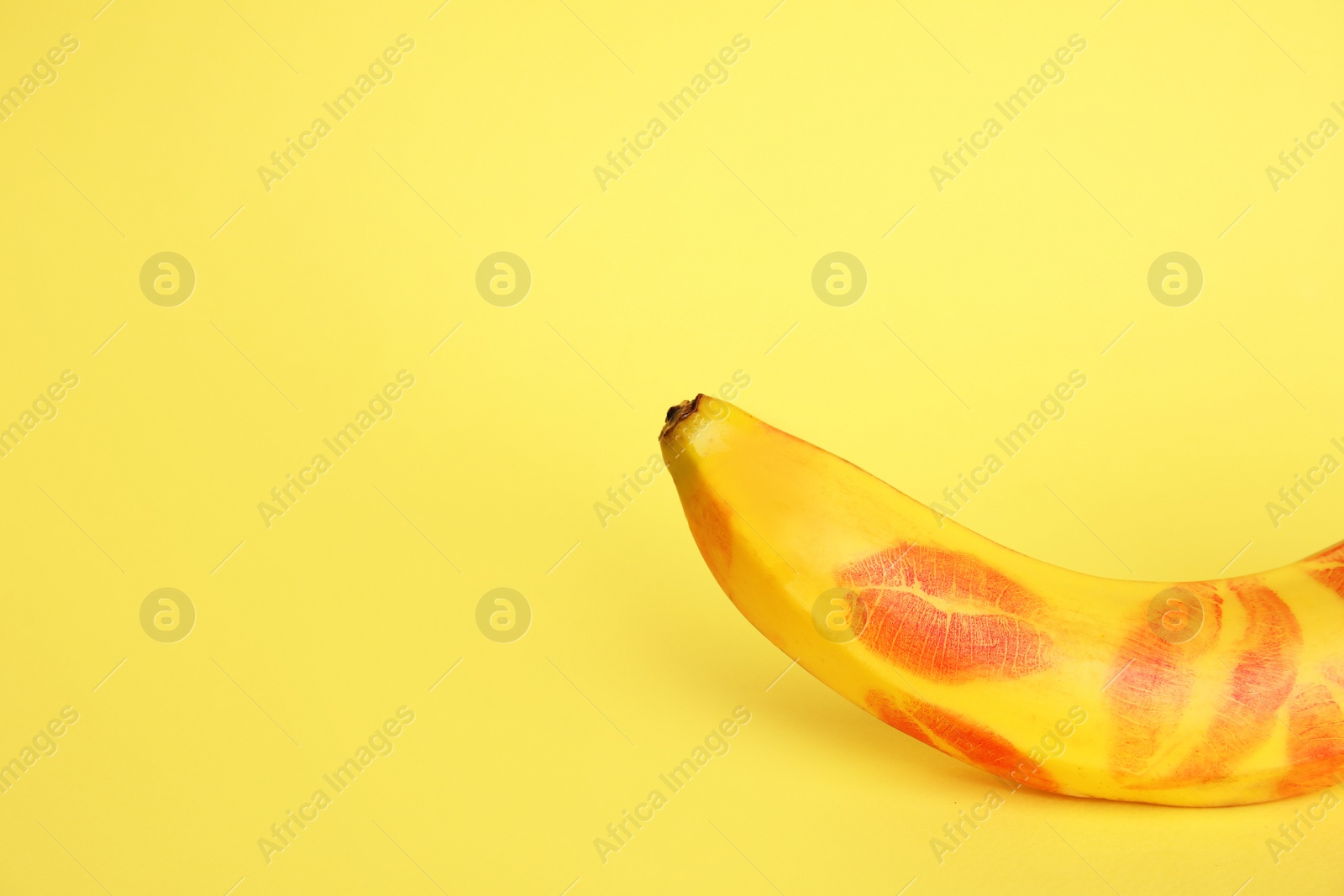 Photo of Fresh banana with red lipstick marks on yellow background, space for text. Oral sex concept