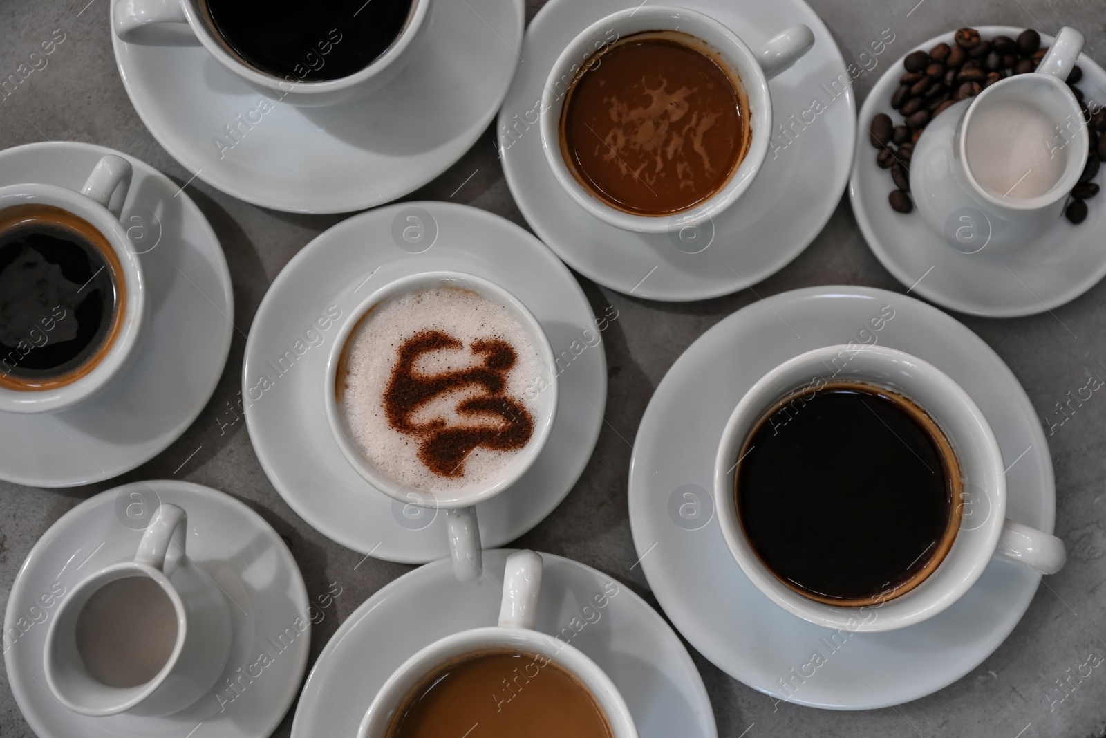 Photo of Cups of fresh aromatic coffee on grey background, top view