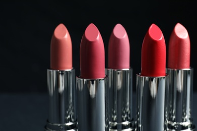 Photo of Different lipsticks on dark background. Cosmetic product