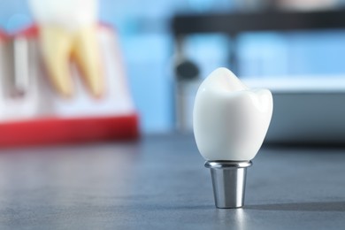 Crown of dental implant with abutment on grey table in clinic, closeup. Space for text