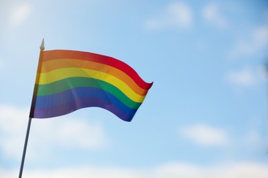 Photo of Bright LGBT flag against blue sky with clouds