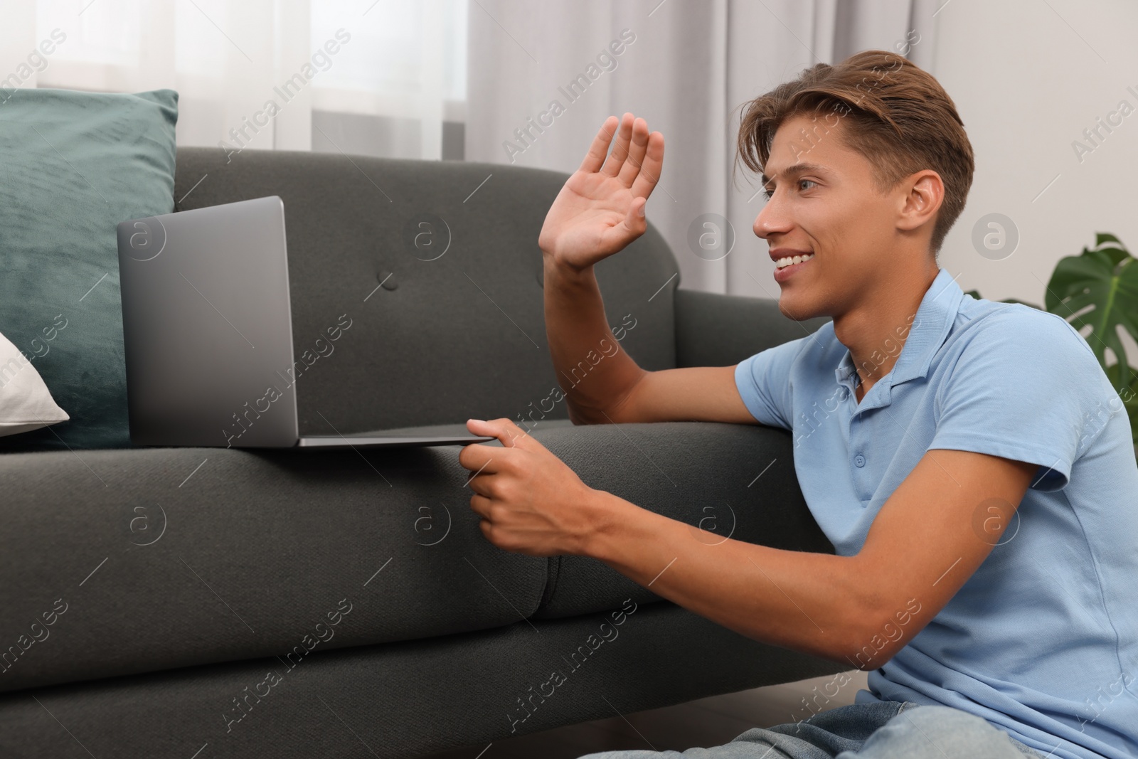 Photo of Happy young man having video chat via laptop on sofa indoors