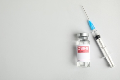Vial with coronavirus vaccine and syringe on white background, flat lay. Space for text