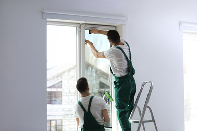 Photo of Professional workers tinting window with foil indoors