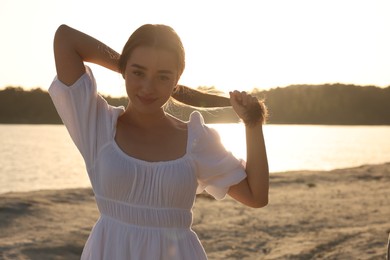 Portrait of beautiful woman near river at sunset