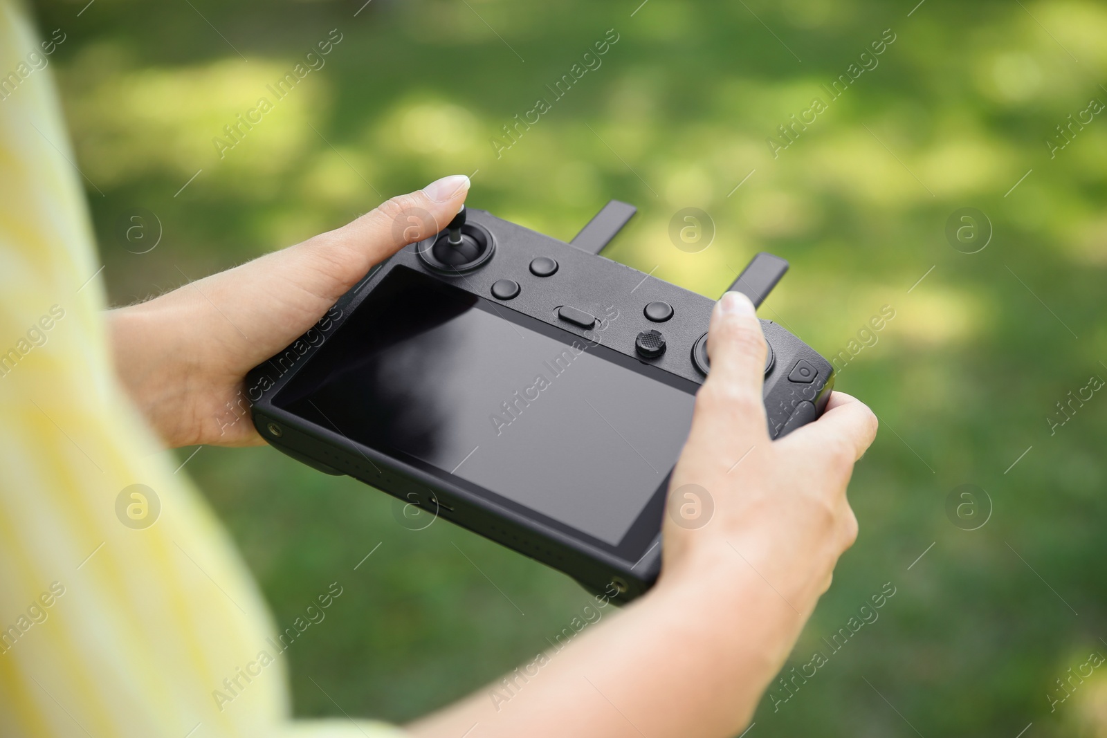 Photo of Woman holding new modern drone controller outdoors, closeup of hands