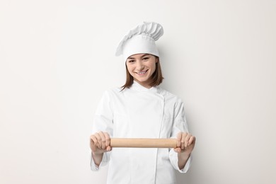 Photo of Professional chef with rolling pin on light background