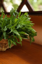 Photo of Beautiful green mint in wicker basket on wooden table
