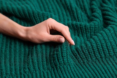 Photo of Woman touching soft green knitted textile, closeup