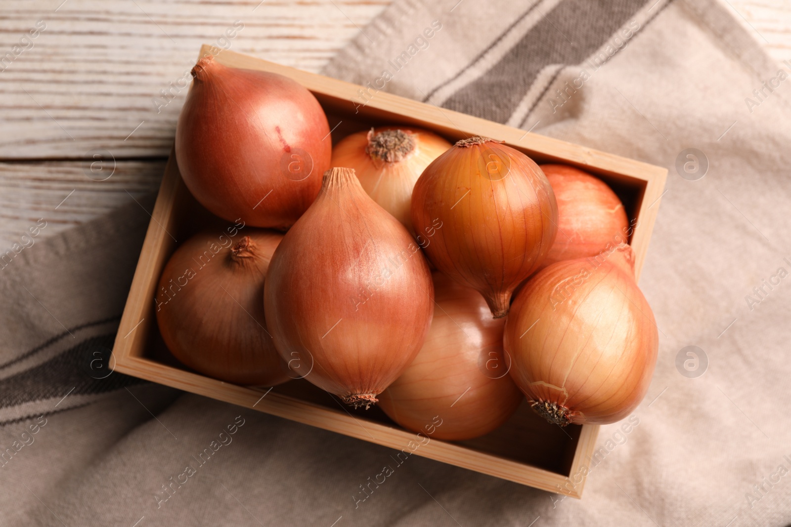 Photo of Crate with ripe onions on white wooden table, top view