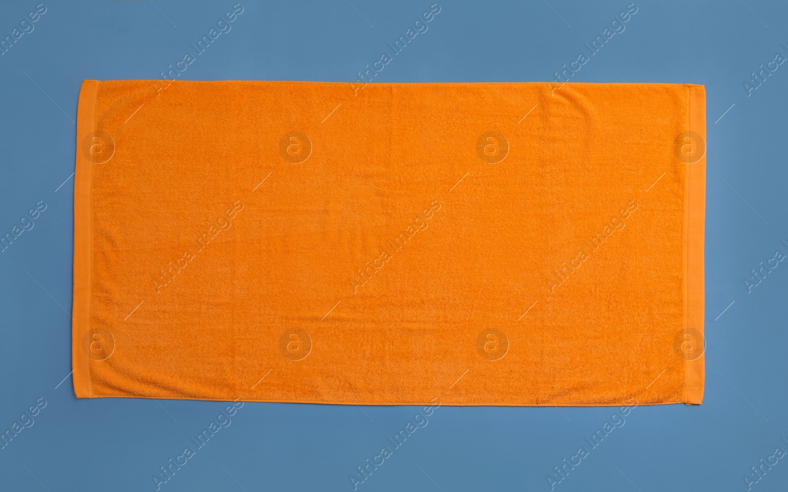 Photo of Orange beach towel on blue background, top view