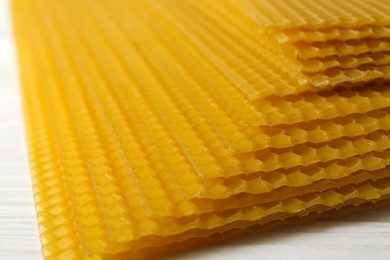 Photo of Natural organic beeswax sheets on white wooden table, closeup