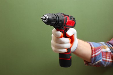 Photo of Handyman holding electric screwdriver on pale green background, closeup