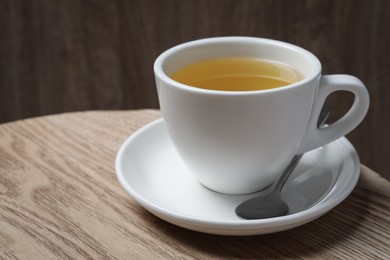 Photo of Cup of aromatic buckwheat tea and spoon on wooden table