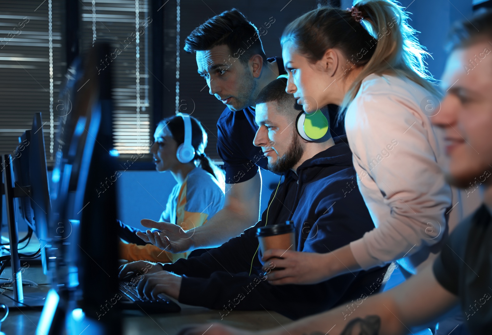 Photo of Group of people playing video games in internet cafe