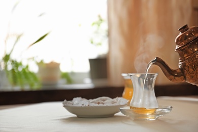 Photo of Pouring hot tea into glass cup on table