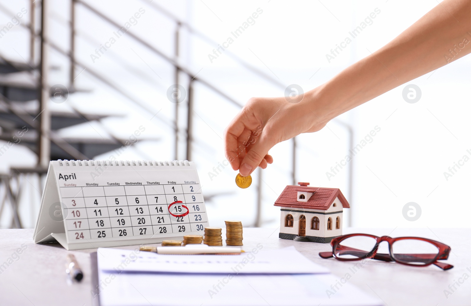 Photo of Woman stacking coins on table. Tax calculation