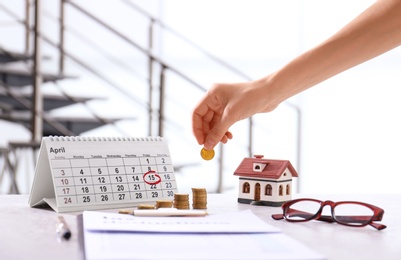 Woman stacking coins on table. Tax calculation