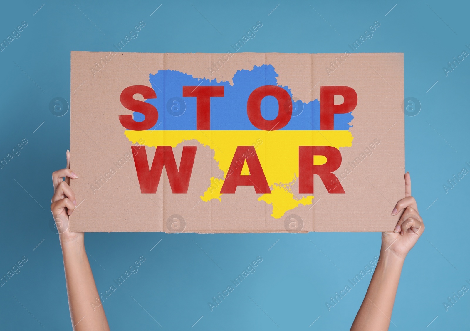 Image of Woman holding poster with words Stop War and map of Ukraine in national colors on light blue background, closeup