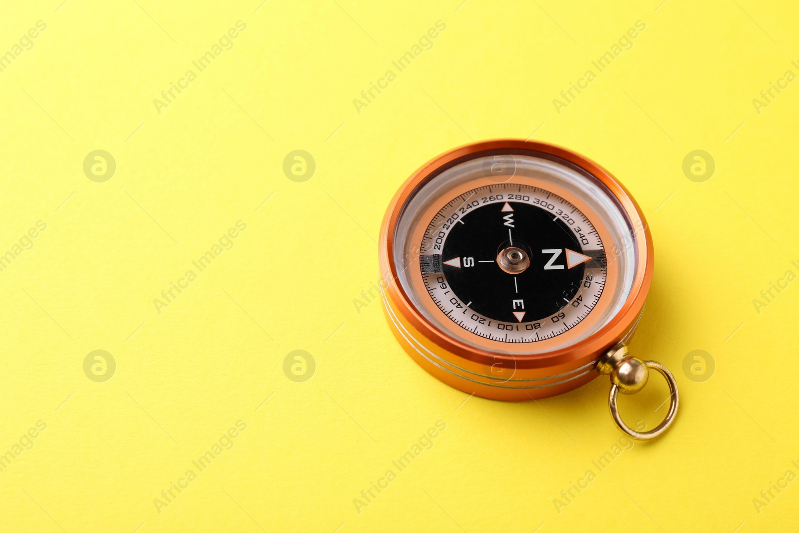 Photo of One compass on yellow background, space for text