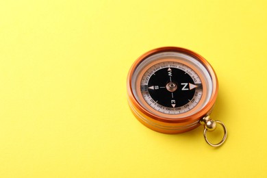 Photo of One compass on yellow background, space for text