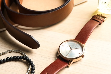 Photo of Luxury wrist watch, belt and bracelets on wooden background, closeup
