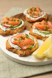 Photo of Tasty canapes with salmon, cucumber, radish and cream cheese on table